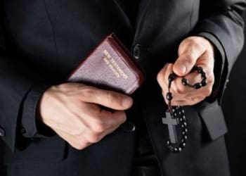 handen van een christelijke priester in het zwart gekleed met een kruisbeeld en een nieuwtestamentisch boek religieuze persoon met bijbel en gebedskralen ingehouden afbeelding 145134 240