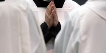 prete in preghiera con le mani giunte